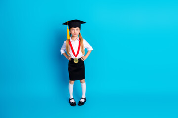 Young girl in graduation cap demonstrating achievement with medal on blue background representing...