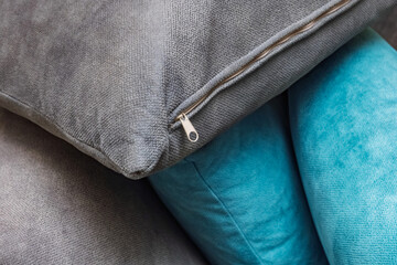 Close-up cushions with zipper detail. A close-up view of stacked cushions featuring a mix of gray and turquoise fabrics. Use for home decor, interior design, and textile themes.