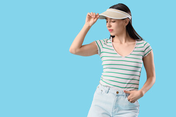 Fototapeta premium Stylish young woman in summer cap on blue background