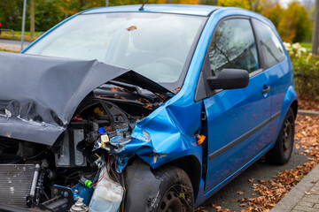 heavily damaged car with crumpled hood and exposed engine, aftermath collision, crash scene, with...