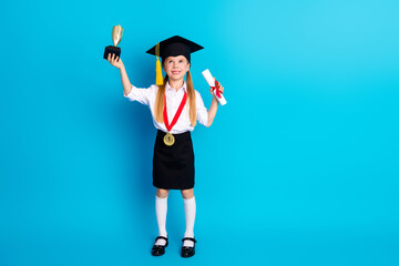 Joyful young schoolgirl celebrating academic success holding a diploma and trophy against a vibrant...