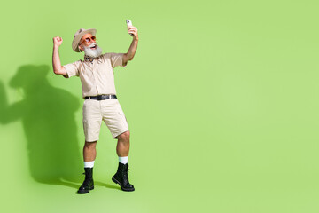 Photo of excited old man traveler wearing safari suit use phone raise fists up near empty space...