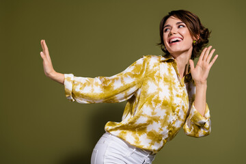 Confident young woman with brunette hair in elegant blouse expressing joy against khaki background