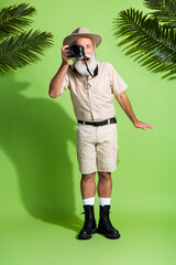 Photo of senior photographer man use digital camera taking photo under tropical palm tree isolated...