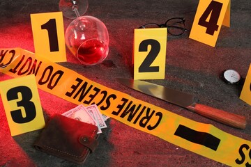 Forensic expert. Yellow crime scene tape, markers and evidences on grey table, closeup