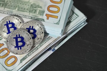Cryptocurrency. Bitcoins and dollar banknotes on black table, above view. Space for text