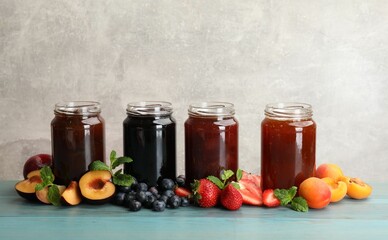 Different jams in jars and ingredients on blue wooden table. Space for text