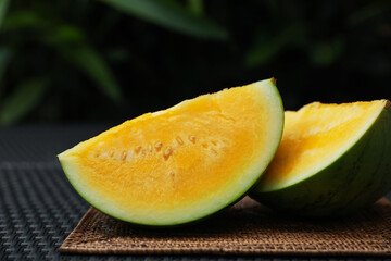 Pieces of ripe yellow watermelon on wicker table, closeup
