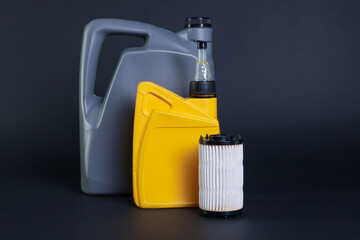 Motor oil in plastic canisters and filter on dark grey background