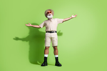 Energetic bearded man wearing safari style outfit on green background embracing adventure and...