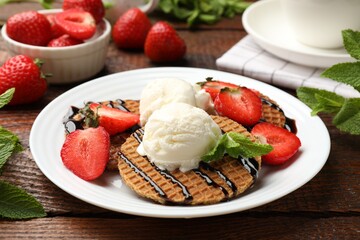 Tasty Dutch waffles (stroopwafels) with strawberries, ice cream and chocolate sauce on wooden table, closeup
