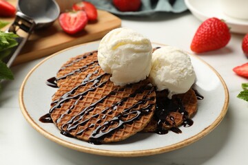 Tasty Dutch waffles (stroopwafels) with ice cream and chocolate sauce on white table, closeup