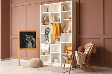 Interior of children's room with shelf unit, chalkboard and armchair