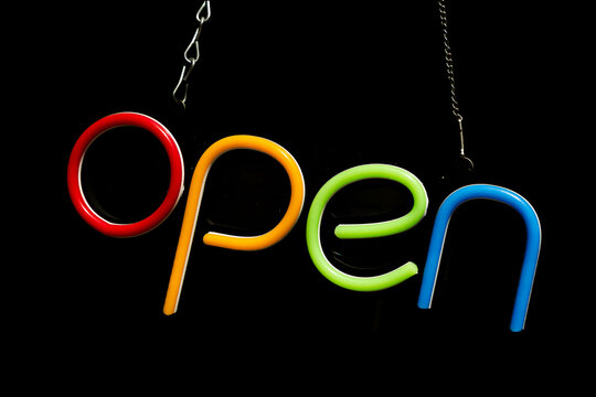 open - a colourful neon sign in front of a black background