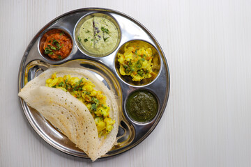 Crispy Masala dosa is a popular South Indian food item served with tomato chutney, coconut chutney, spicy potato masala, or aloo ki sabzi and sambar. Copy space. Crunchy Rice crepes.
