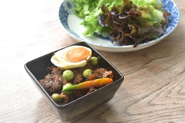 spicy fried chop pork Thai chili pasted topping salty egg in bowl eat couple fresh green oak vegetable