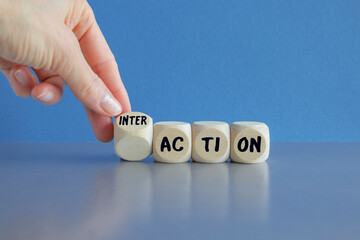 Hand turns dice and changes the word action to interaction. Beautiful blue background. Business and...