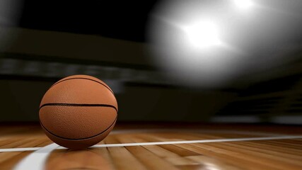A basketball rolling on a polished wooden court with bright overhead lights illuminating the scene - Powered by Adobe