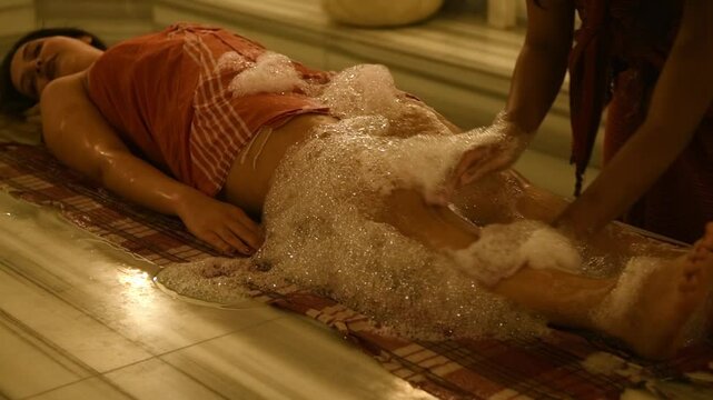 Close-up slow motion of traditional foam massage being performed on woman in elegant hotel hammam spa