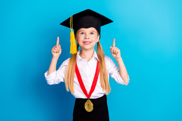 Young schoolgirl in graduation attire holding a gold medal on a blue background symbolizing...