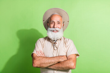 Photo of safari tourist travel guide look smiling with crossed arms wear suit hat isolated green...