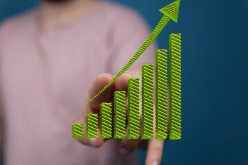 Stock photo of a hand interacting with a 3D green upward trending graph, symbolizing growth and...