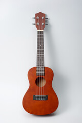 Ukulele made of natural wood of dark color photographed on a white background.