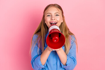 Happy young girl holding a megaphone and smiling on a vibrant pink background promoting...