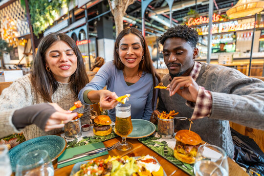 Friends sharing nachos and burgers at restaurant table
