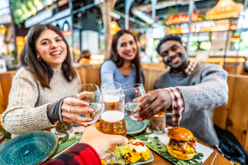 Friends toasting drinks at restaurant, celebrating with beer and water