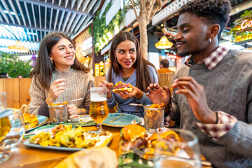 Young friends eating burgers and fries at the restaurant inside a food court