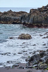 Waves hitting volcanic shoreline rocks
