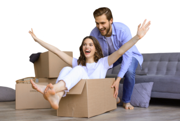 Happy couple is having fun with cardboard boxes in new house at moving day, woman riding sitting in cardboard box while man pushing it on a transparent background
