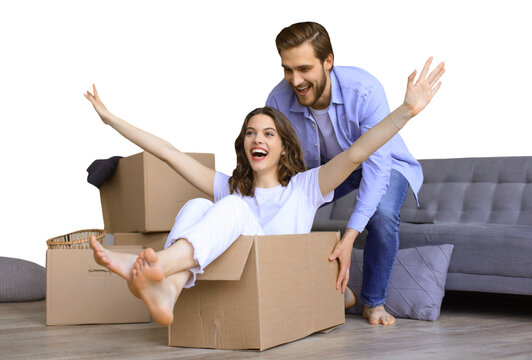 Happy couple is having fun with cardboard boxes in new house at moving day, woman riding sitting in cardboard box while man pushing it on a transparent background
