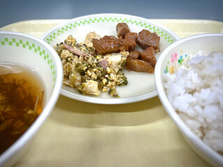 Japanese school lunch tray set featuring native foods of Okinawa, such as goya champuru (bitter melon stir-fry with tofu and egg) and rafute (pork braised belly).