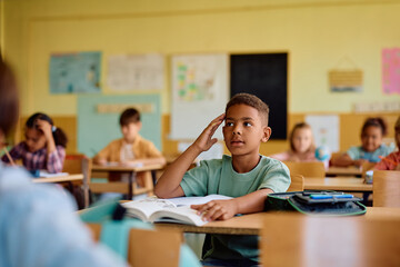 Pensive black schoolboy during class in classroom.