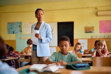 Black teacher and her students during test in classroom.