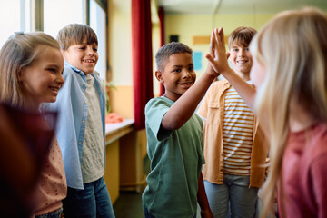 Happy kids greeting in classroom at school.