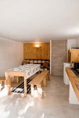 Cozy Alpine Dining Area Interior with Wooden Wall Accent, White Tablecloth, Bench Seating, and Modern Lighting in a Ski Lodge Style Space