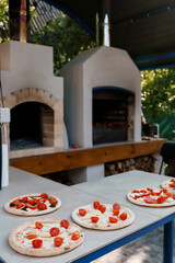 Rustic Outdoor Wood-Fired Pizza Oven and Prepared Pizzas: Warm Italian Cuisine, Stone Texture, Garden Setting, Summertime Food Photography