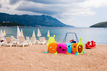 Colorful children's playground on a sandy beach. Seaside recreation, summer vacation, and family-friendly tourism by the coast.