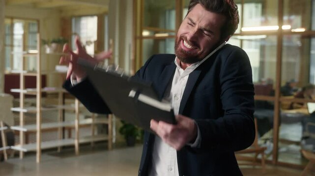 Business angry Caucasian man businessman talk mobile phone multitask arguing in office mad manager worker employee male guy quarrel smartphone overwork problem holding notepad papers documents stress