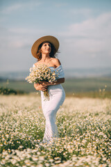 Woman Daisies Field: Summer day, lady with bouquet stands in blooming daisies field, looks into distance.