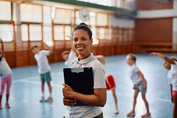 Happy black sports teacher during physical education class at school looking at camera.