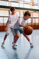 Naklejka premium Elementary students playing basketball at school gym.