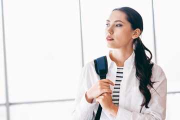 Young female traveler with backpack waits at the airport, contemplating her journey and future...