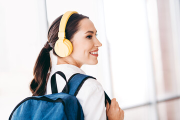 Young woman with headphones and backpack enjoying travel in casual fashion in a modern setting