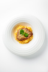Spaghetti with hearty meat sauce and fresh basil served on a white plate, isolated on white background. Ideal for Italian cuisine, lunch, or dinner food concepts