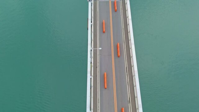 Vital freight link in Tacloban reduced to single lane during major 2-year repairs - top down view of road, changing to landscape bridge with mountains
