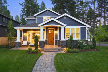 Beautiful home exterior in evening with glowing interior lights and landscaping